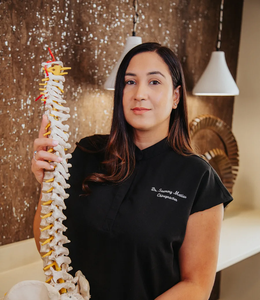 Dr. Soammy L. Matias, D.C., founder of Matias Health Chiropractic, holding a spine model